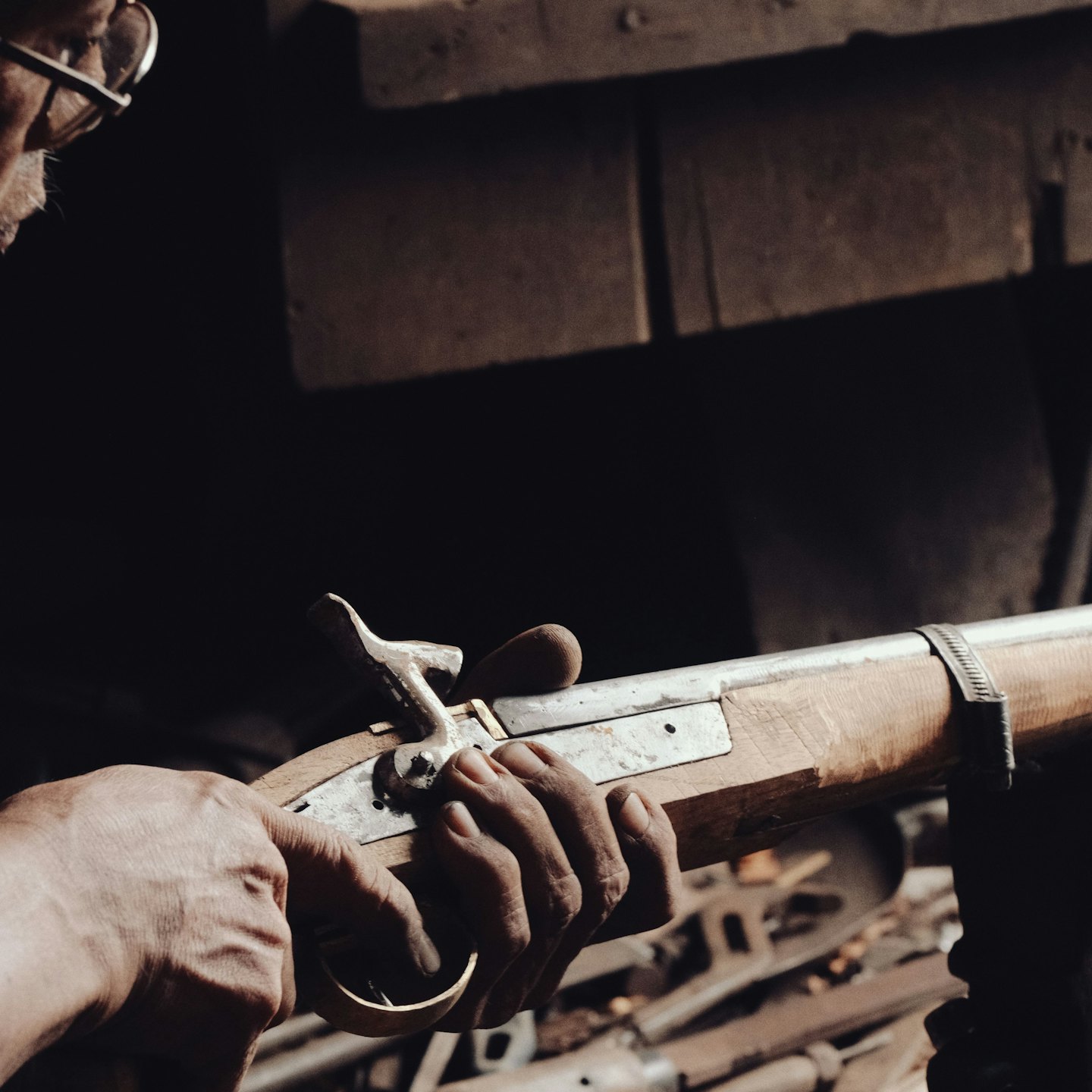 A craftsman inspects the metalwork on an antique wooden firearm.