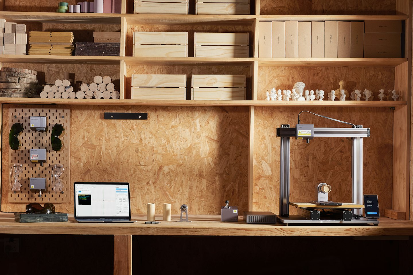 Laser engraver and 3D printer on a workbench with laptop.